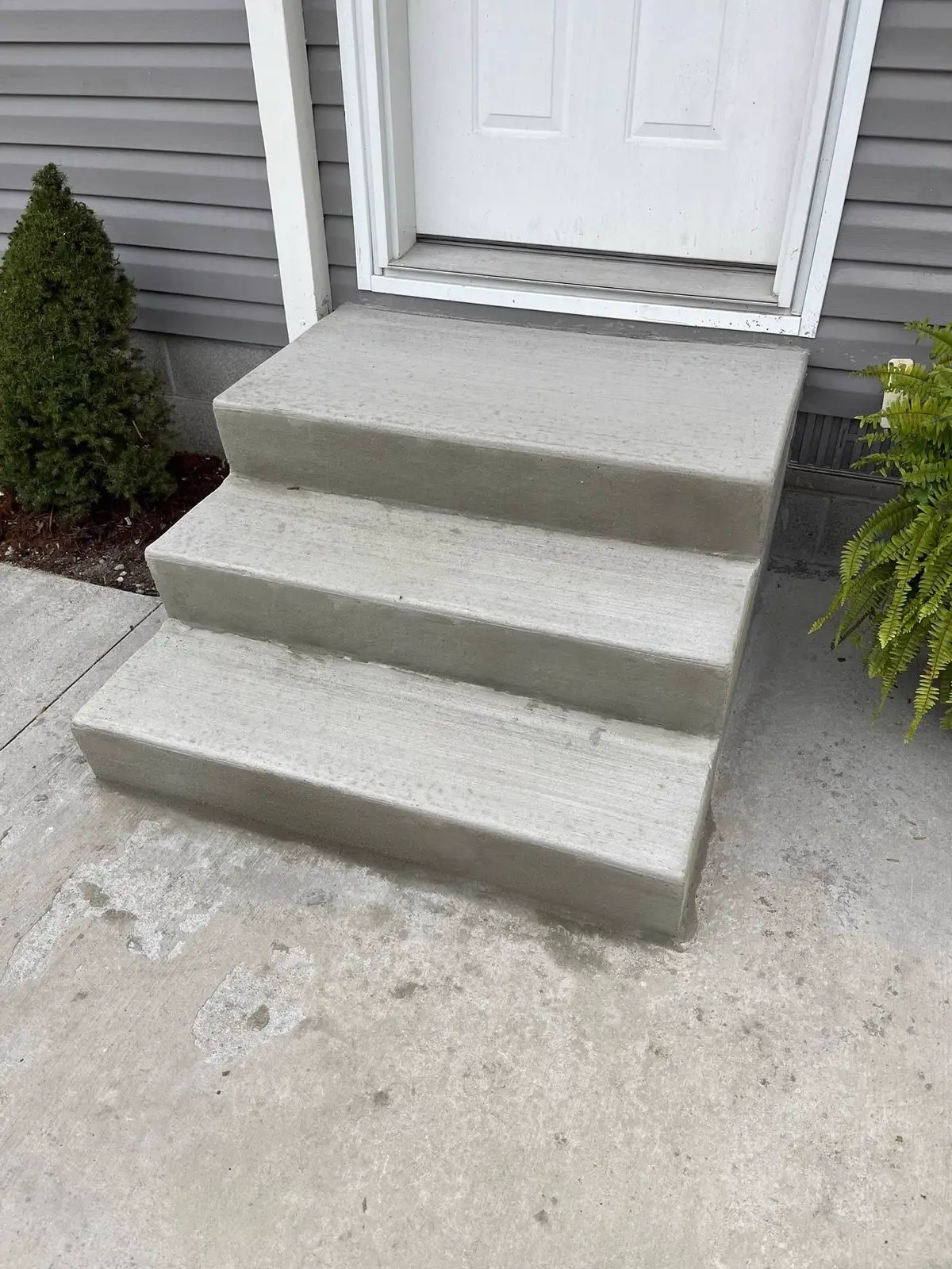 New concrete front steps poured beside an entry
